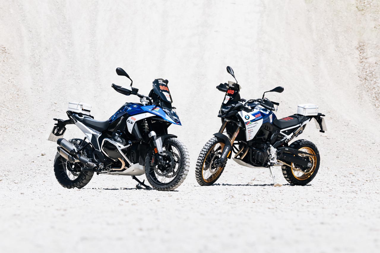 Pilotos del equipo BMW GS Trophy preparando sus Motos de Competición R 1300 GS Trophy para una etapa del GS Trophy 2024, con el paisaje de Namibia de fondo