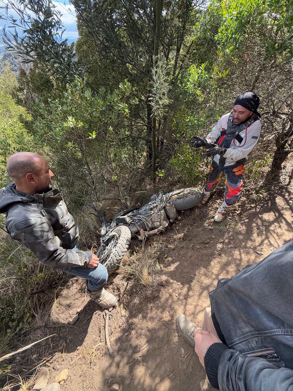 Moto caída en un sendero de tierra accidentado después de quedar atascada en un surco profundo.