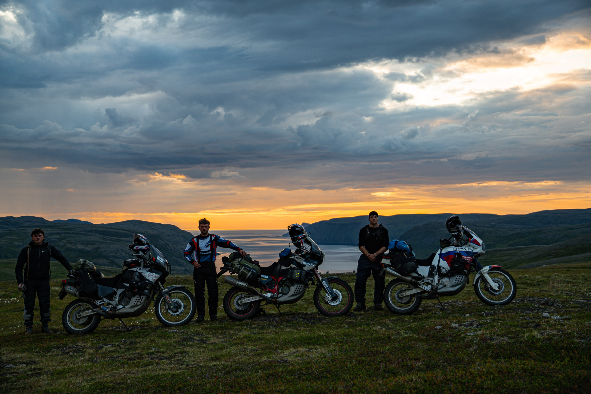 Tres pilotos en motos de aventura Honda XRV750 Africa Twin navegando por una carretera de grava en la Trans Euro Trail sueca.