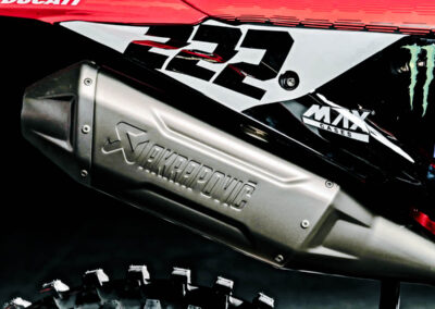 "Close-up of the bespoke Akrapovič exhaust system on the Ducati Desmo450, highlighting its intricate craftsmanship and the lightweight titanium construction, with the Ducati logo visible.