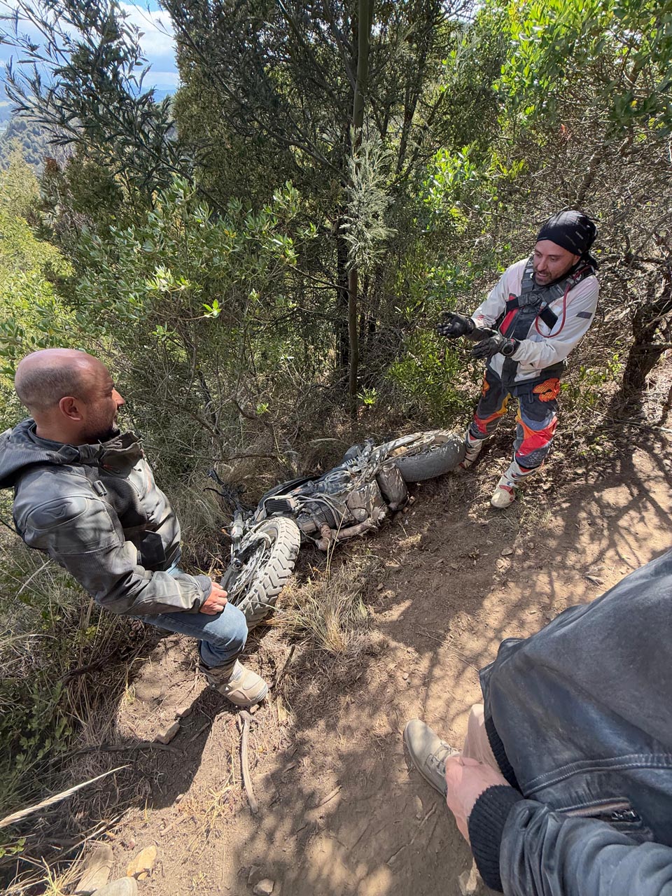 Fallen motorcycle on a rough dirt trail after getting stuck in a deep rut.